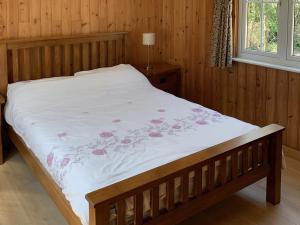 1 dormitorio con 1 cama con colcha blanca y flores en The Hideaway, en Breamore
