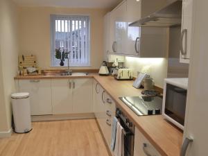 a kitchen with white cabinets and a counter top at Red House in Torquay