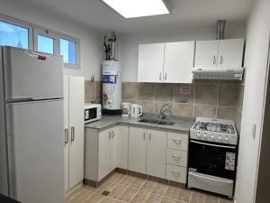 a kitchen with white cabinets and a white refrigerator at Monoambiente céntrico in Comodoro Rivadavia +3 photos