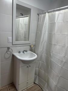 a white bathroom with a sink and a mirror at Monoambiente céntrico in Comodoro Rivadavia