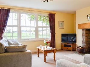 a living room with a couch and a tv at Osprey Cottage - Uzq in Kirkton of Airlie