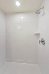 baño blanco con ducha con cabezal de ducha en Entire Furnished Luxury Apt in Lake Merritt en Oakland