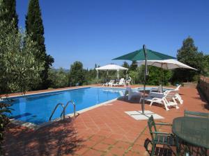 a swimming pool with chairs and umbrellas next to it at Casale del Vacanziere in Certaldo
