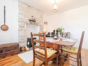 a dining room with a table and a stone wall at Dragonfly Cottage in St Austell
