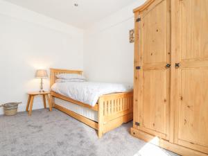 a bedroom with a bed and a wooden cabinet at Dragonfly Cottage in St Austell