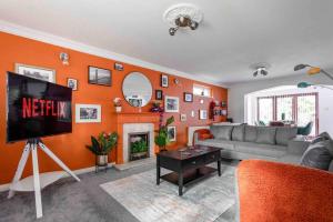 a living room with an orange wall with a tv at The Orange House Langdon Hills 