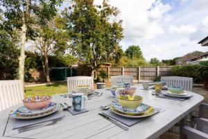 una mesa blanca con platos y tazones. en The Orange House Langdon Hills 