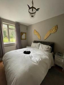 eine schwarze Katze auf einem weißen Bett in der Unterkunft Cosy & Chic 1BD Flat - 6 Minutes to Notting Hill! in London