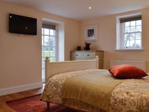 a bedroom with a bed and a flat screen tv at Gardeners Cottage in Montrose