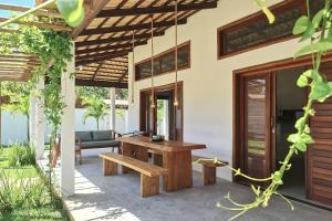 a patio with a wooden table and a bench at Chalés em Jericoacoara por Carpediem in Jijoca de Jericoacoara
