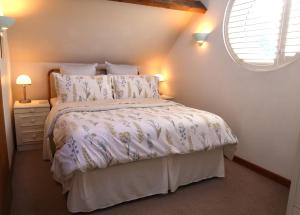a bedroom with a bed with a white comforter and a window at Charming 2-Bed Cottage in Toft Knutsford in Knutsford
