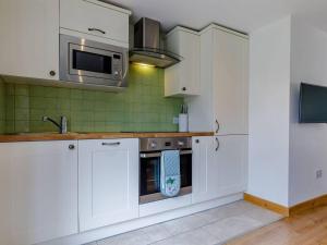 a kitchen with white cabinets and a sink and a microwave at Delightful Cottage with 2 Bedrooms near Knutsford in Knutsford +16 photos