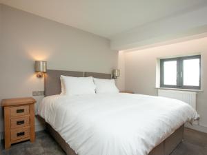Un dormitorio con una gran cama blanca y una ventana en The Oyster en Turnchapel