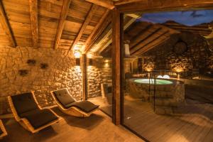 a patio with a tub and chairs on a deck at Alpinchalet Apartment Alpenrose in Ortisei