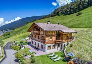 a large wooden house on a green hill at Alpinchalet Apartment Alpenrose in Ortisei