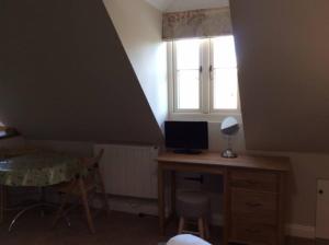 Country Studio Apartment في Charlton: غرفة بها مكتب وبه جهاز كمبيوتر ونافذة