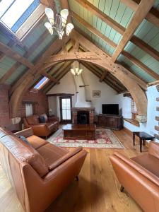 a living room with leather furniture and a vaulted ceiling at Swallows Barn in Penrith