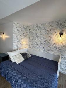 ein Schlafzimmer mit einem großen Bett mit einer blauen Decke in der Unterkunft Studio lumineux en bord de mer in Pléneuf-Val-André