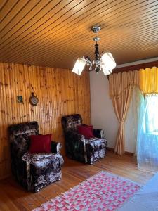 a living room with two chairs and a ceiling at Goni Guest House in Tepelenë
