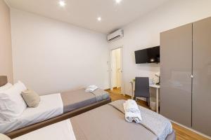 um quarto com duas camas, uma escrivaninha e uma TV em White Gold em Nápoles