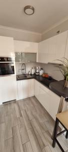 a kitchen with white cabinets and a wooden floor at Apartament Madelain in Jelenia Góra