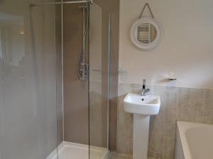 a bathroom with a glass shower and a sink at Silvershell View in Port Isaac