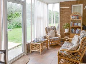 a screened in porch with rocking chairs and windows at Silverdale in Bacton