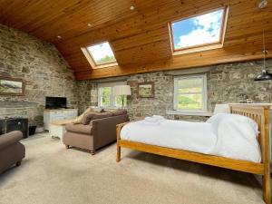1 dormitorio con cama y pared de piedra en Glacour Studio Cottage en Bridgend