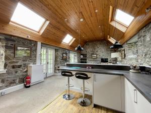 a kitchen with wooden ceilings and a stone wall at Glacour Studio Cottage in Bridgend