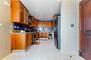 a kitchen with wooden cabinets and a white tile floor at Habitación Privada con vista al mar Ámbar, Malecon Santo Domingo in Santo Domingo