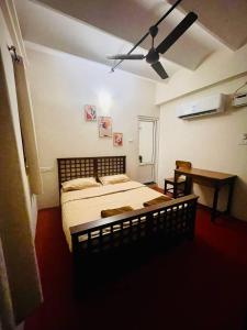 een slaapkamer met een bed en een plafondventilator bij Parambara Heritage in Pondicherry