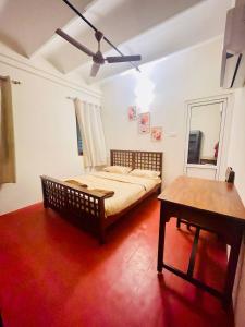 a bedroom with a bed and a table and a ceiling fan at Parambara - A Heritage Stay in Puducherry