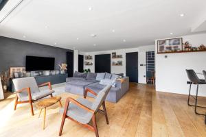 uma sala de estar com um sofá cinzento e cadeiras em House at the heath em Royston