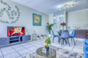 a living room with a television and a table and chairs at Serene Retreat on Sandton in Sandton