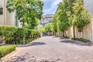 a brick road with trees and bushes next to a building at Serene Retreat on Sandton in Sandton