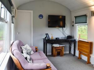 a living room with a couch and a tv at The Carriage in Bridge of Dee