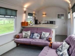 sala de estar con sofá púrpura y cocina en The Carriage, en Bridge of Dee