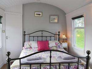 a bedroom with a black bed with a pink pillow at The Carriage in Bridge of Dee