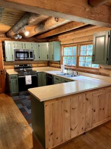 une cuisine avec des placards en bois et un grand îlot dans l'établissement Rustic Retreat Cozy Log Cabin, à Halifax