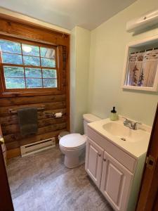 baño con aseo y lavabo y ventana en Rustic Retreat Cozy Log Cabin, en Halifax
