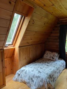 Cama en una cabaña de madera con ventana en Rustic Retreat Cozy Log Cabin, en Halifax