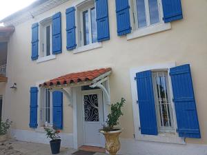 una casa con persianas azules y una puerta en Mas des 2 paons, en Villedaigne