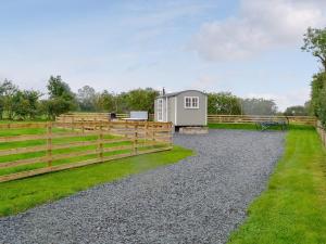Gilcrux的住宿－Greengill Farm Shepherds Hut- Ukc3632，一个带栅栏和房屋的谷仓