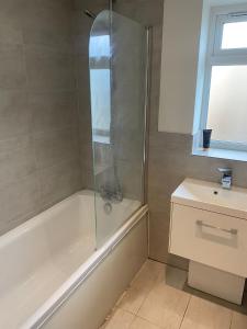 a bathroom with a shower and a tub and a sink at Large Luxury appartment in Cobham