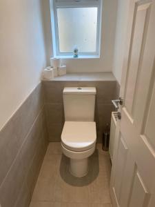 a white toilet in a bathroom with a window at Large Luxury appartment in Cobham