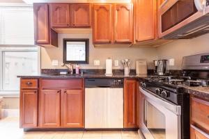 a kitchen with wooden cabinets and a stove top oven at The Brick House Wooster Sq at Yale with Skyline Deck and WD in New Haven
