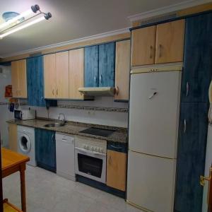 cocina con armarios de madera y nevera blanca en Apartamento Coqueto 10min centro en Oviedo