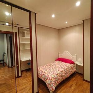 um pequeno quarto com uma cama e um espelho em Apartamento Coqueto 10min centro em Oviedo