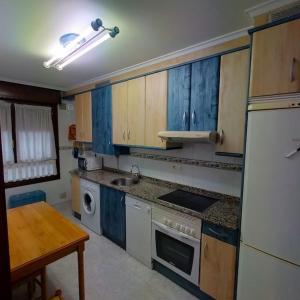 uma cozinha com armários azuis e um frigorífico branco em Apartamento Coqueto 10min centro em Oviedo
