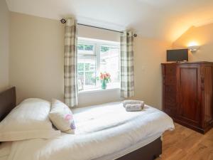 ein Schlafzimmer mit einem großen Bett und einem Fenster in der Unterkunft 2 Luckington Stables-w8322 in Holcombe